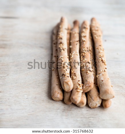 Fresh baked homemade grissini bread sticks with sesame seeds on wooden background. Selective focus