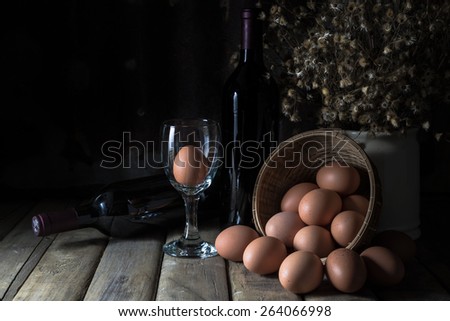 Still life with eggs, wine bottle, dry little flower on wood table and rustic steel plate background