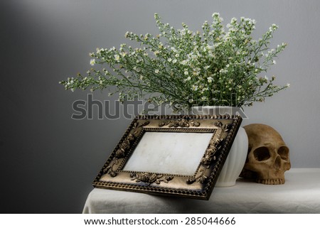 Still life with classic frame, flowers in vase and skull