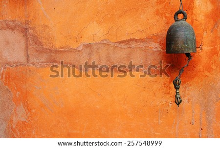 Old little bell on orange wall