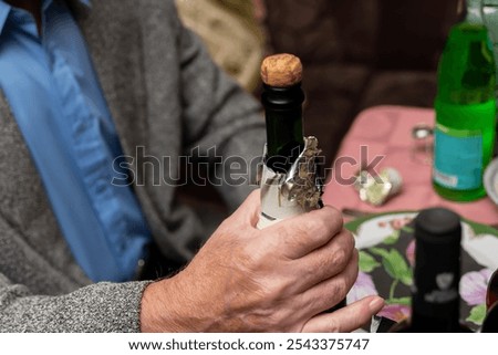 Foto Bild Älterer Mann öffnet Champagnerflasche während der Weihnachtsfeier zu Hause