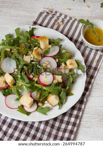 salad with radish  arugula and pine nuts. salad dressing, useful power, healthy lifestyle, extra virgin olive oil.
