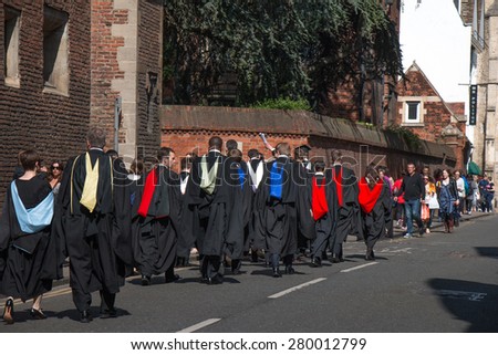 Cambridge, UK - May 16, 2015: Colleagues Graduation Day of students from University of Cambridge. University Students in gown are walking on the street going back to their colleges.