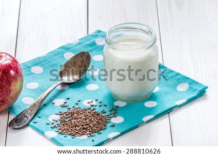 yogurt with flax seeds and old silver spoon on white wooden table
