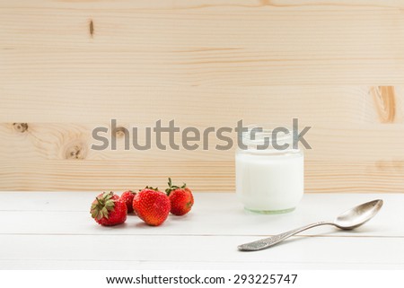 yogurt with old silver spoon and strawberry  on white table at wooden background