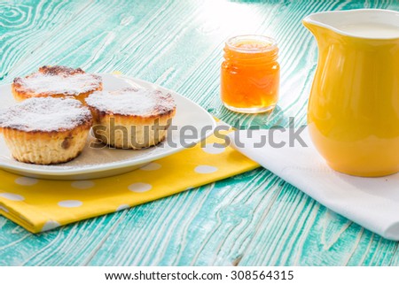 cheesecakes and jar of apricot jam and yellow milk jug on turquoise colored wooden table
