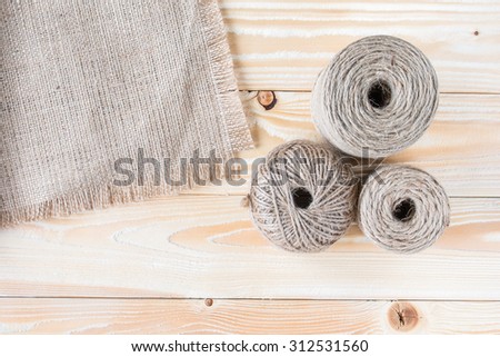 three skeins of jute yarn with sackcloth on wooden table. top view. copy space