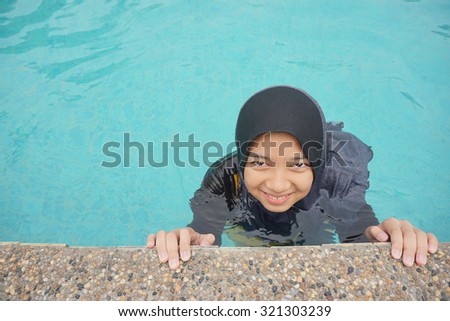 Young muslim girl swimming at pool