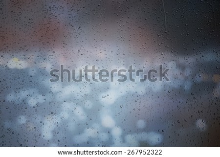 Drops of rain on window with abstract lights