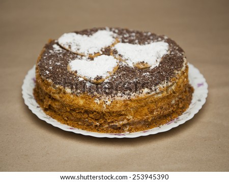 cake with chocolate crumb. Honey cake. Cake hearts. Cake on warm background. Cake on white plate. Baked cake. White powder cake. Bake food. Baking. Vanilla