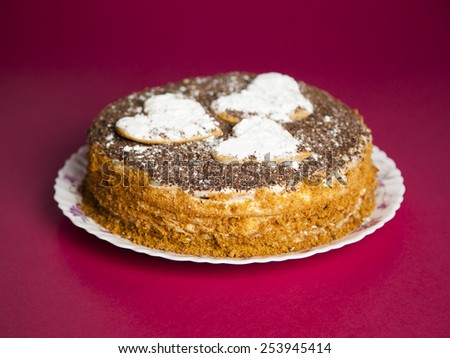cake with chocolate crumb. Honey cake. Cake hearts. Cake on red background. Cake on white plate. Baked cake. White powder cake. Baking food