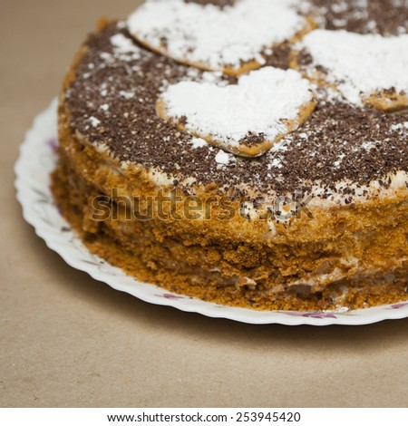 Cake with chocolate crumb. Honey cake. Cake hearts. Cake on warm background. Cake on white plate. Baked cake. White powder cake. Bake food. Baking