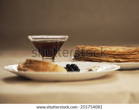 Russian pancakes with honey on table. Russian cuisine. Taste pancake. Black currant on white plate with pancakes.Blini. Maslenitsa. Pancake week. Butter Week. Cheesefare Week