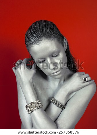 Silver woman face with ring, bijou on red background.