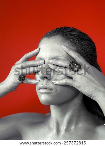 Silver woman face with ring, bijou on red background. Strange kind of woman. Look, view