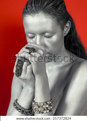 Silver woman face with ring, bijou on red background.
