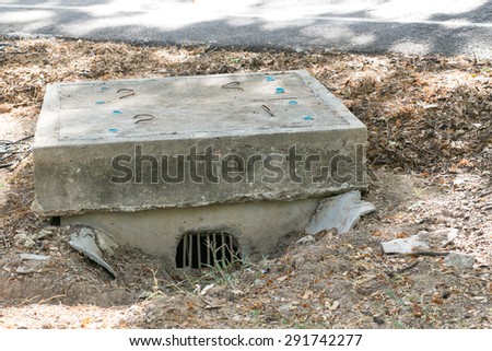 Cement manhole beside road.