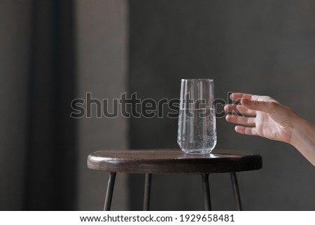 a woman's hand takes a clear glass of water, on a gray background, drinking fresh water for health, the rate of water per day to saturate the body, proper nutrition  Stok fotoğraf © 