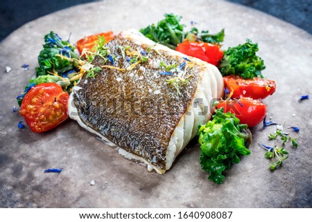 Gourmet fried European skrei cod fish filet with kalette and tomatoes as closeup on a modern design plate Stock foto © 