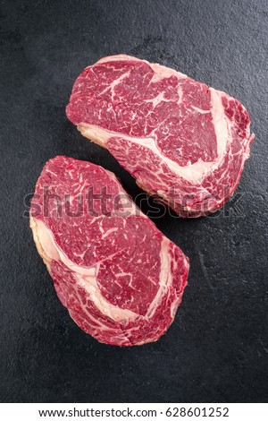 Similar – Image, Stock Photo Two raw marbled rib-eye steak on cutting board with rosemary, garlic and green pepper