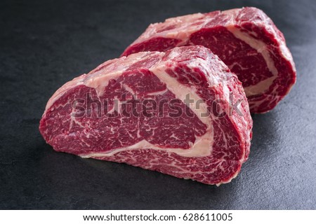 Similar – Image, Stock Photo Two raw marbled rib-eye steak on cutting board with rosemary, garlic and green pepper