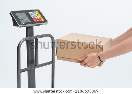 Woman weighing a parcel for shipping. Parcel scale isolated on white background. Foto d'archivio © 