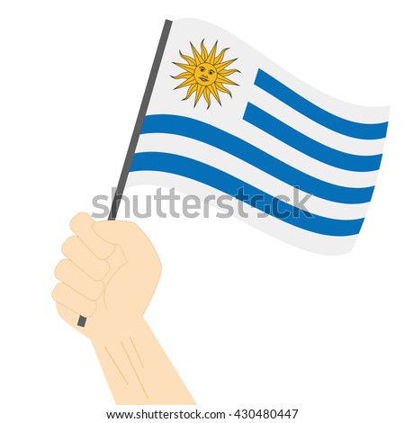 Hand holding and raising the national flag of Uruguay