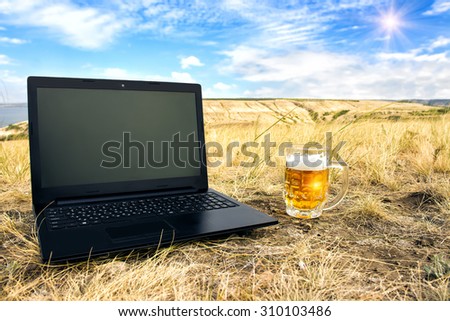 Mug of cold beer and laptop