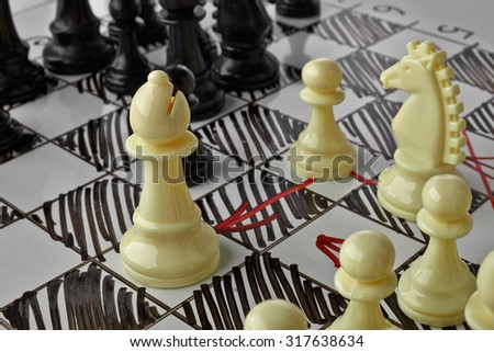 Chess. The white Bishop is under attack. White board with chess figures on it. Plan of battle.