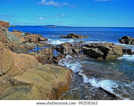 Lovely and dramatic landscape showing the tide rolling in among boulders of the scenic, rocky Acadia coastline at Thunder Hole.