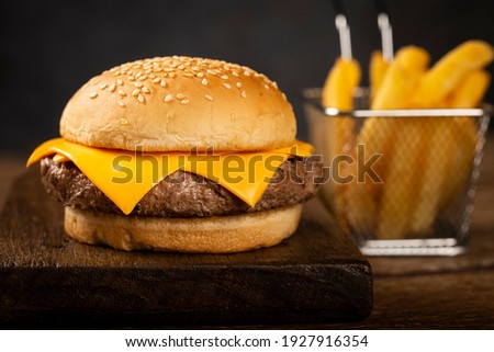 Tasty hamburger with french fries and sauces on dark background.