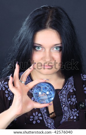 Beautifu smiling black-haired witch holding the magic sphere