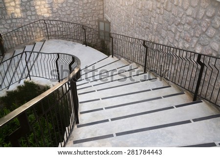 Castle style concrete stairways with handrail and stone veneer wall.