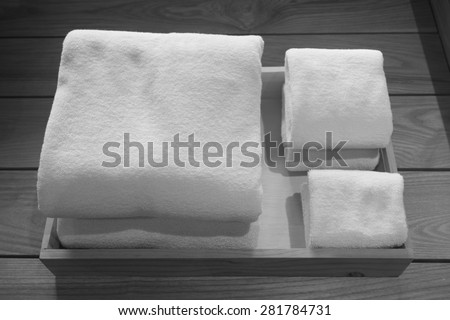 Folded different sizes of white towels in a wooden tray (black and white)