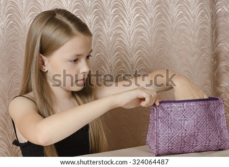 the girl of 9 years opens a ladies\' handbag which faces it.