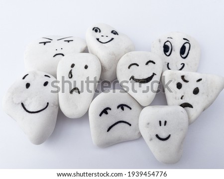 Emotion management concept, stones with painted faces symbolize different emotions. We are all different, but all together, learning to manage emotions. Soft background, white stones.