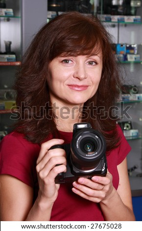 The woman - seller in photographic shop advertises the camera