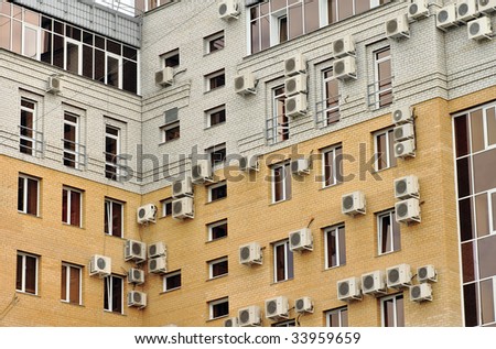 Windows and air conditioners on a modern office building. Comparison with birds\' nests