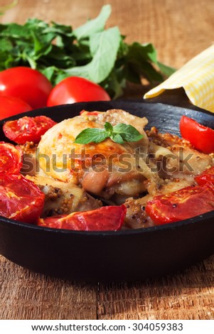 Cooked chicken with tomato, garlic and mustard on the rustic table, selective focus