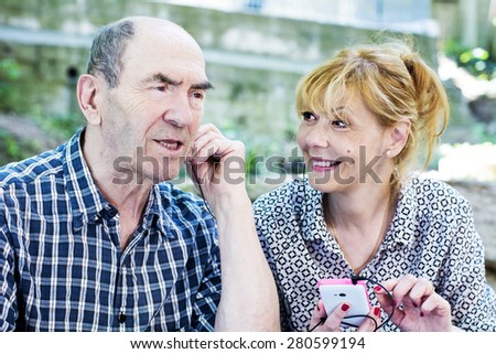 The old man listens to music from a mobile phone