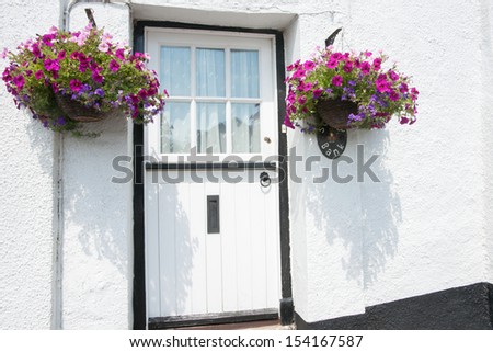 White exterior door, with black door frame and hanging baskets