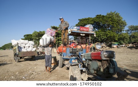YANGON, MYANMAR - NOVEMBER 5;Men unloading sacks of goods from a tractor and trailer on the bank of Irrawaddy River the entry port for Yangon on November 5, 2013, Yangon, Myanmar,