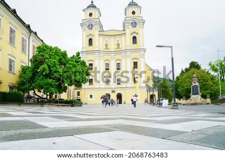 Mondsee Austria - September 6 2017; Tall towers and bright yellow facade over entrance f St Michael's Basilica beyond black and white patterned forecourt. Stock fotó © 