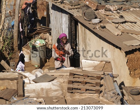 SOWETO, SOUTH AFRICA - AUGUST 15; Woman carries child through the shanty homes in Soweto, South Africa on August 15, 2007. The living conditions of the shanty town can be clearly seen.