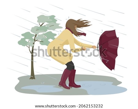 Dangerous condition with rain and wind. A woman tries to hold onto her umbrella during a strong storm. 