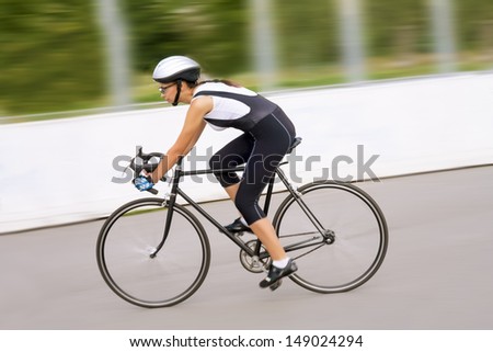 young caucasian female woman riding on the race bike outdoors. panning technique used. horizontal shot