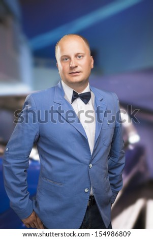 Portrait of a Man in Suite and Bow Tie Against Blurred Car Background. Vertical Image