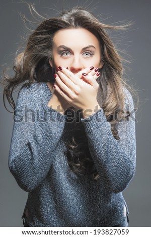 Portrait of Surprised and Silent Female Model Against Gray Background with Hands put on Mouth. Vertical Image