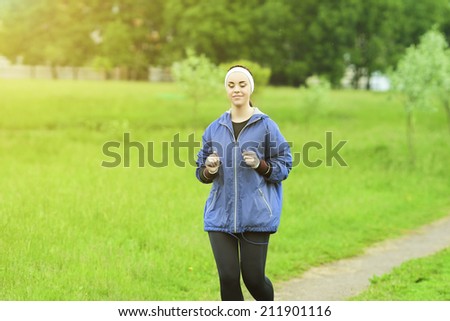 Jogging and Fitness Concepts: Portrait of Beautiful Caucasian Young Woman Jogging  and Listening to Music Outdoors. Horizontal Image Composition