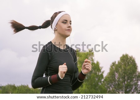 Jogging and Fitness Concepts: Portrait of Beautiful Caucasian Young Woman Jogging  and Listening to Music Outdoors. Horizontal Image Composition